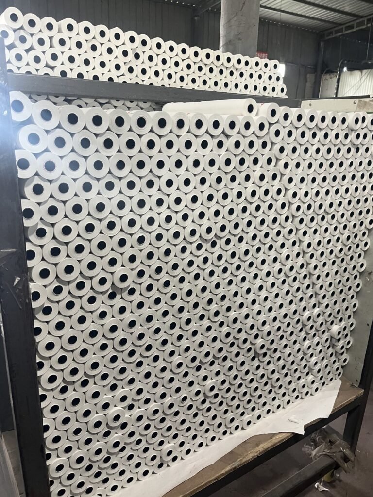 Finished paper rolls stored on racking against a warehouse wall