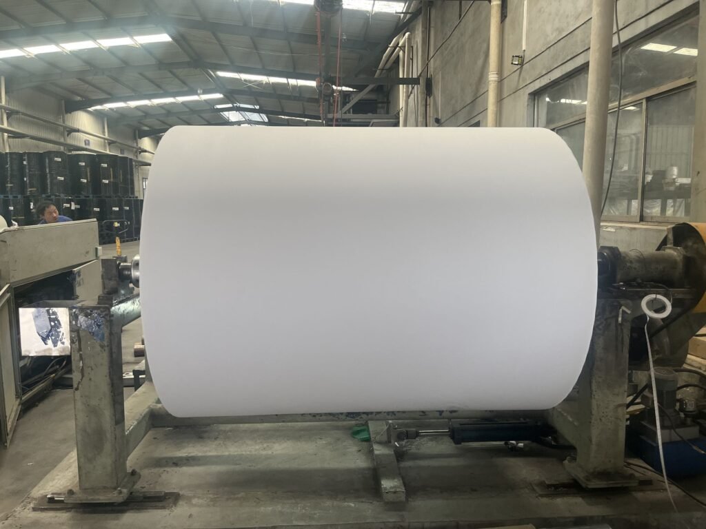 White jumbo roll mounted on a slitting machine