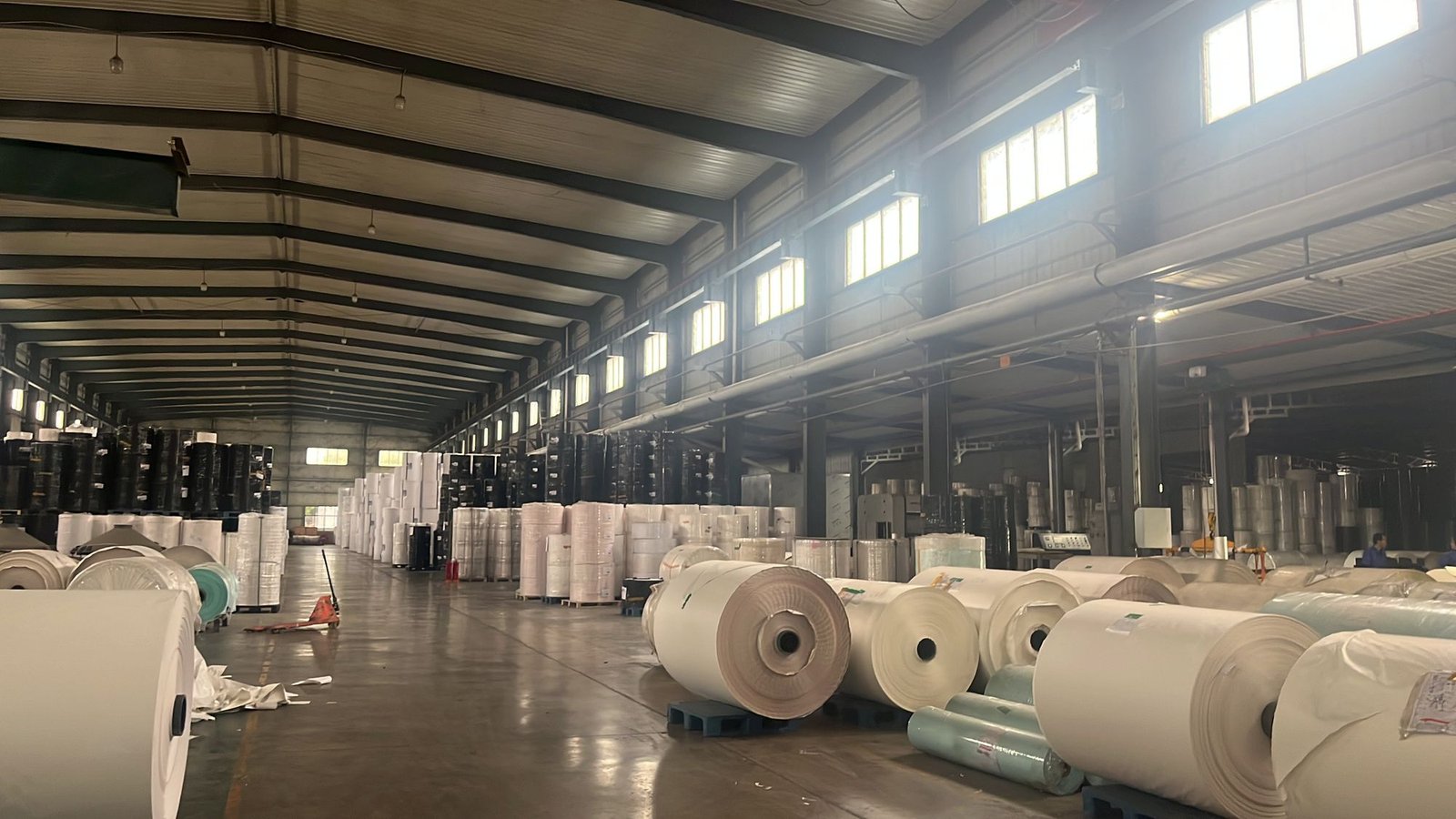 Jumbo paper rolls stacked along a warehouse aisle